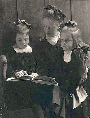 Three young girls reading a book.